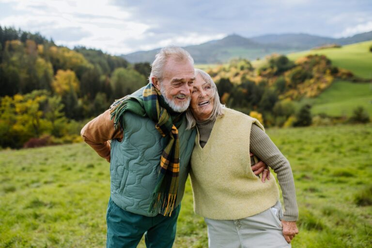 Happy senior couple walking in autumn meadow.